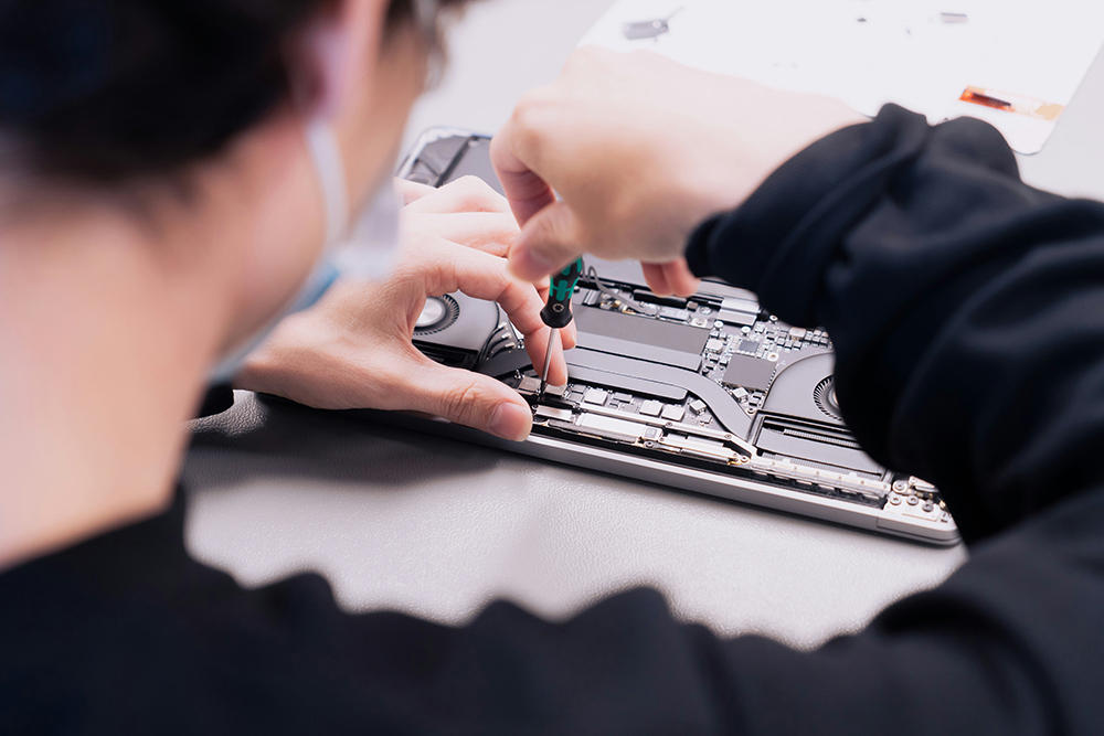 person using screwdriver on computer motherboard - right to repair